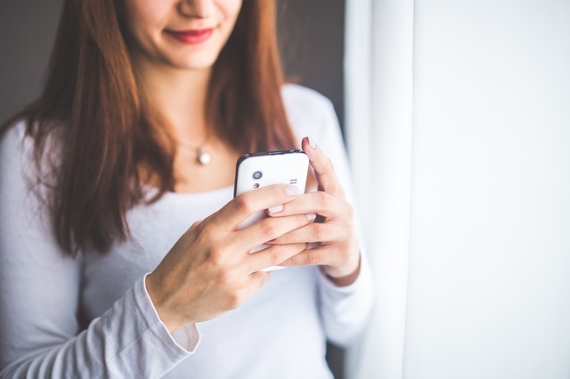 Femme en t-shirt blanc avec son mobile en mains