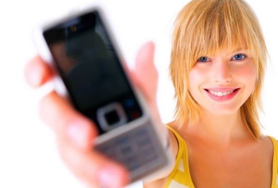 Jeune femme blonde tenant un téléphone mobile