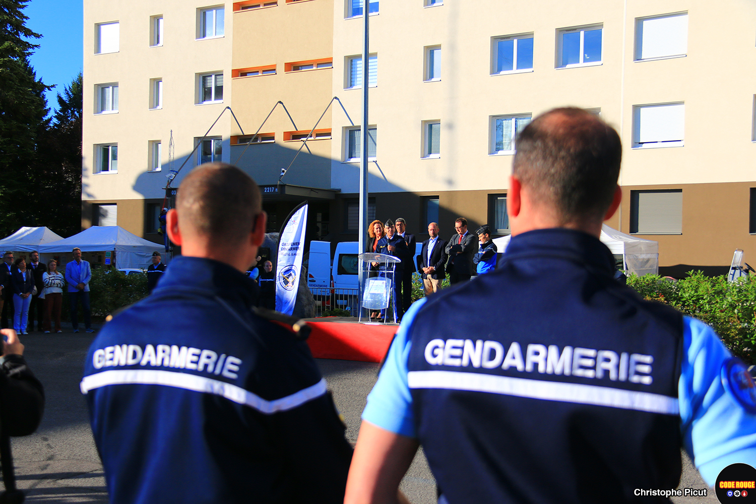 Deux gendaremes, de dos, assistent à un discours