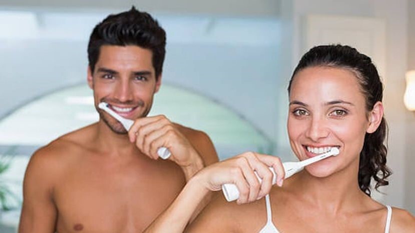 Un homme et une femme utilisant des brosses à dents électriques