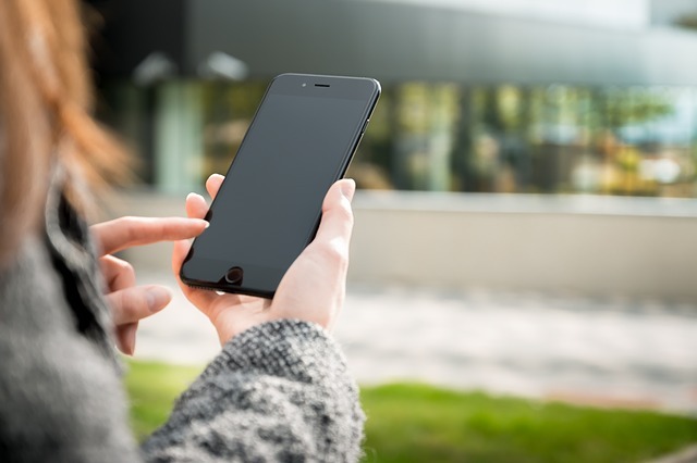 Fille avec pull gris et un smartphone dans sa main