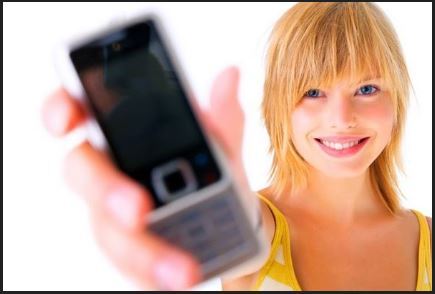 Une femme blonde tenant un téléphone mobile