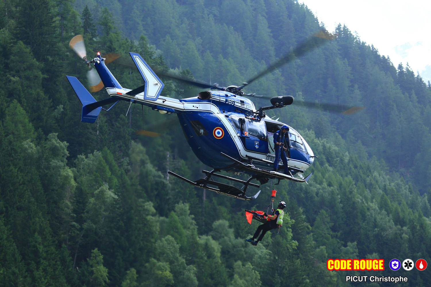 Un hélicoptère de la gendarmerie en vol lors d'une démonstration ; un homme est héliporté grâce à un câble