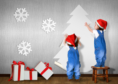 Enfants coolant au mur un grand découpage de sapin de Noël