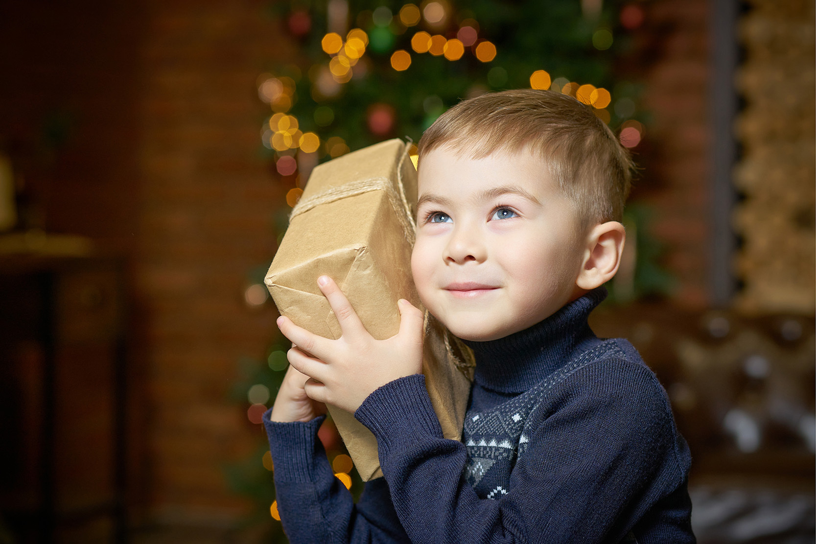 Petit garçon tenant un cadeau emballé en papier kraft contre son visage