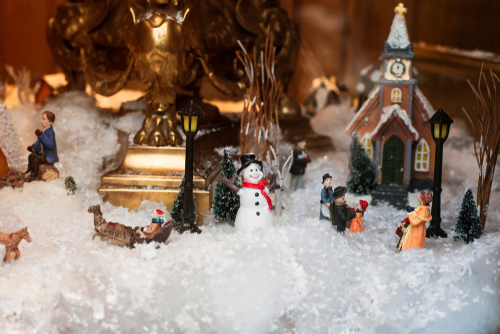 scène de village reproduite avec des santons, une église miniature et des lampadaires sur de la neige artificielle